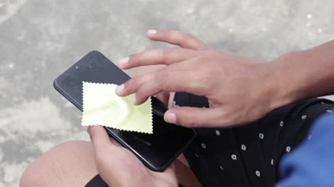 Close-up of man hand using wet wipe and sanitizer to clean cell phone screen. Vidéo 137882782