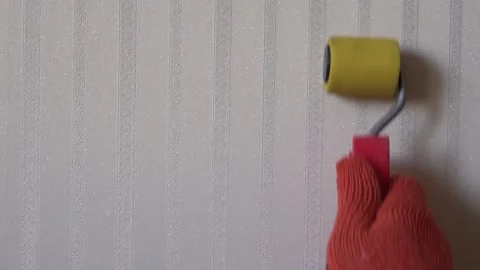 Close-up of man hand with wallpaper roller smoothes fresh pasted wallpaper Stock Footage 133646678