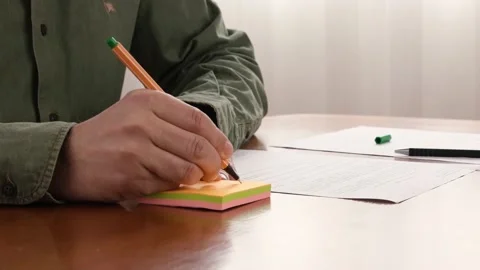 Close-Up Of A Man Hand Writing A Note On Sticky Notes And Putting It On Paper. Stock Footage 150264812