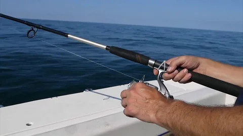 Close up man hands are turning the reel of the fishing rod fishing from the boat Stock Footage 116704348