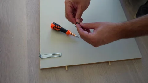 Close up of man hands assembling furniture at home on wooden floor, high Vidéo 258658402