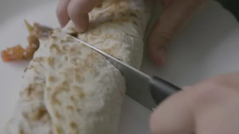 Close-up of man hands cut a kebab, roll, doner with a knife on the plate Stock Footage 240875891