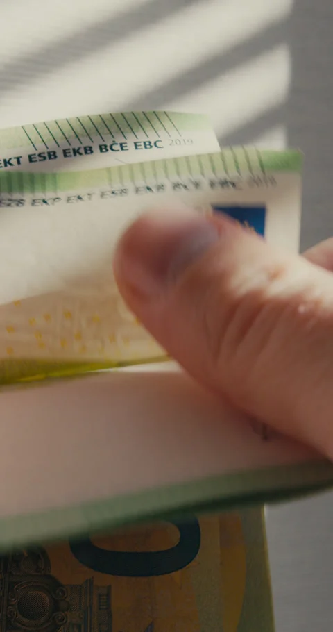 Close-up of a man hands flipping through and counting 100-euro banknotes against 스톡 동영상 347009927