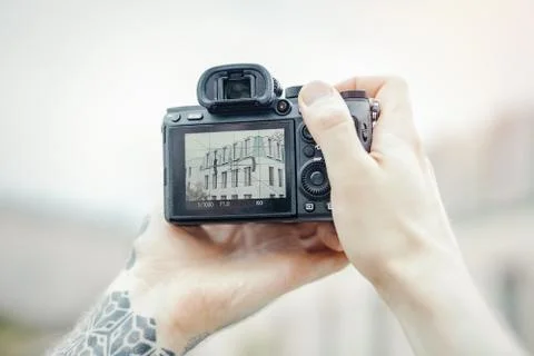 Close up of man hands holding camera and making photos of modern building. Stock Photos