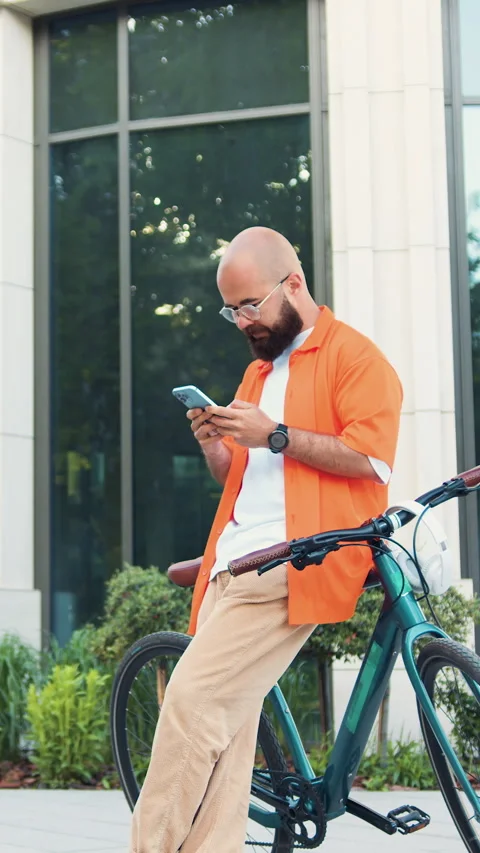 Close-up of man hands holding smartphone while walking with bike near office cen Stock Footage 333510908