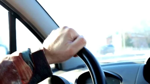 Close-up of man hands holding on steering wheel while driving a car in sunny Stock-Footage 336265611