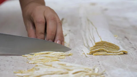 Close-up man hands with knife cutting dough to prepare noodles, homemade pasta Stock Footage 305156219