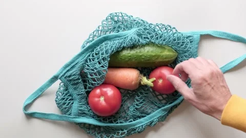 Close up of man hands puts vegetables into eco string bag at supermarket Video stock 219916886