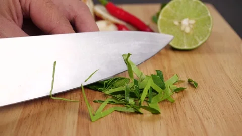 Close-up of Man hands slice Kaffir lime leaves in pieces on cutting board Stock Footage 141096316