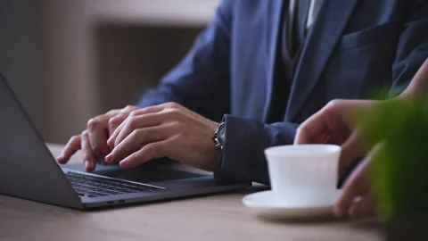 Close-up of man hands typing on a laptop, assistant brought a cup of coffee Stock Footage 233717488