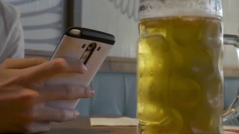 Close up of man hands using smartphone in restaurant with beer. 스톡 동영상 76759064