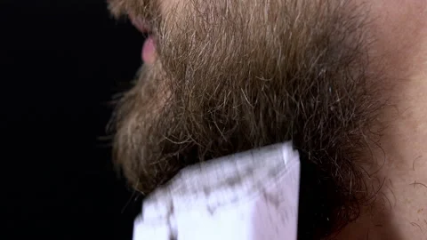 Close-up of a man having a beard trimmed with a trimmer on a black background Stock Footage 144641445