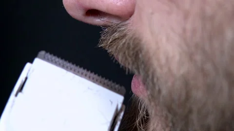 Close-up of a man having a beard trimmed with a trimmer on a black background Stock Footage 144641617