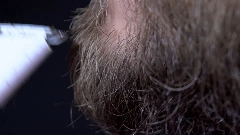 Close-up of a man having a beard trimmed with a trimmer on a black background Stock Footage 144688444
