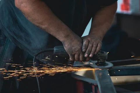 Close up on a man held an angle grinder to cut an iron with sparks Stock Photos