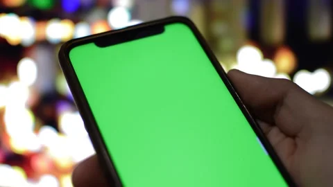 Close-up man hold iphone with green screen during night in a blur city. 스톡 동영상 228907393