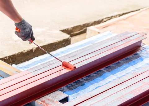 Close up man hold paint roller painting rustproof metal beam. Stock Photos