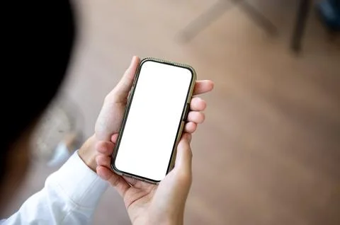 Close up man holding and looking at white screen phone in hands sitting ind.. Stock Photos