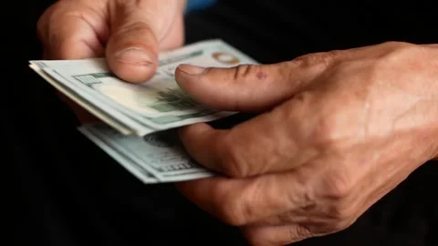 Close-up of a man holding a bundle of 100 dollar bills. Financial safety net and Stock Footage 162943479
