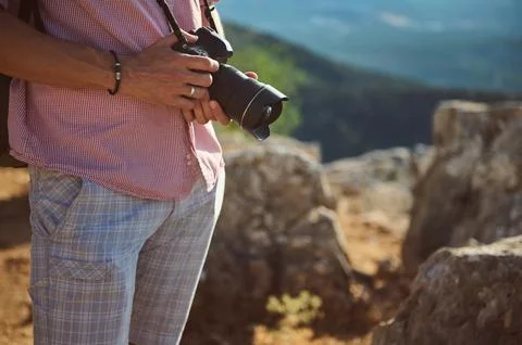 Close-up of man holding camera while standing outdoors in a natural rocky e.. Stock Photos