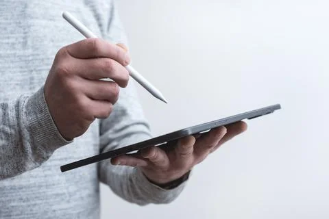 Close up of man holding digital tablet in one hand and stylus pen in the othe Stock Photos