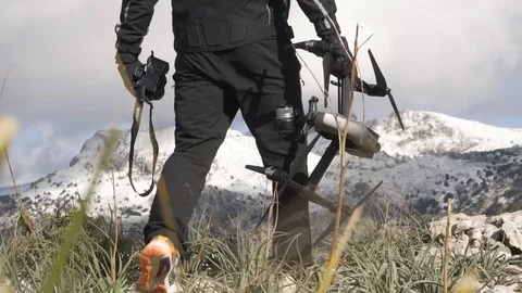 Close up of man holding drone on cliff with snow in background Stock Footage 100433741