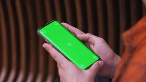 Close-up of a Man Holding Green Mock-up Screen Smartphone and Using Touchscreen Stock Footage 243374493