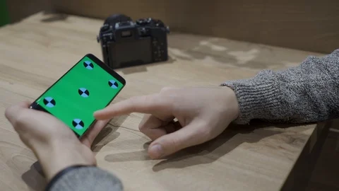 Close-up of a man holding a green-screen smartphone and viewing photos from a Stock Footage 102283987