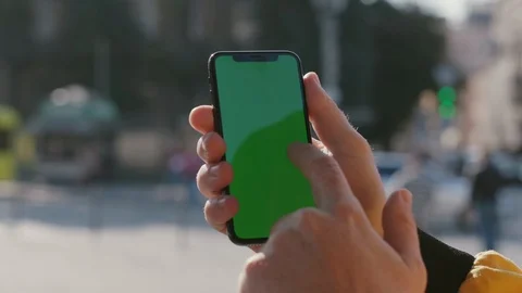 Close-up of man holding greenscreen device tapping on modern vertical smartphone Stock Footage 117427877
