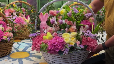 Close-up of a man holding a large Easter basket with pink fresh flowers and bunn Stock Footage 306974806