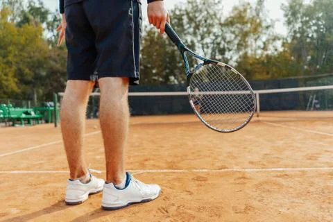 Close up of man holding racket while waiting for ball serving at tennis court. Stock Photos