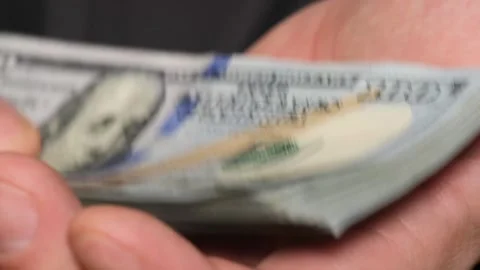 Close-up of a man holding a stack of dollars in his hands. The man received a Stock Footage 241442727
