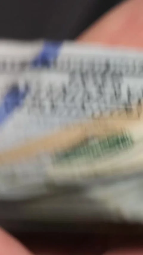 Close-up of a man holding a stack of dollars in his hands. The man received a Stock Footage 248420359