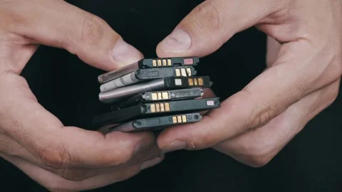 Close-Up of a Man Holding Various Used Smartphone Batteries. Stock Footage 316487186