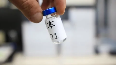 A close up from a man holding a vial with a liquid labelled as sample in chinese Stock Footage 254600574
