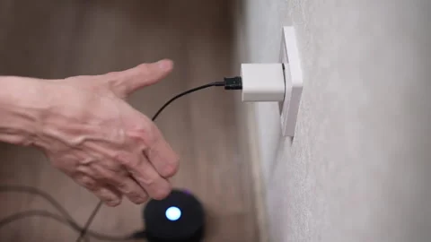 Close-up of man inserting plug of smart speaker power supply into wall outlet Stock Footage 301394522