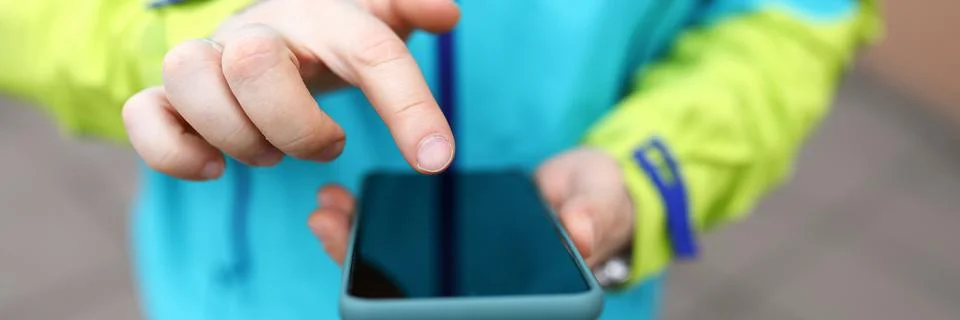 Close-up man in jacket clicks touch screen phone Foto stock