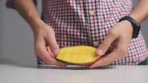 Close up. A man in the kitchen demonstrates a mango cut into cubes. Mango fruit Stock Footage 120844866