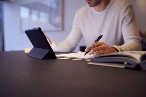 Close Up Of Man In Kitchen Working Or Studying From Home Using Digital Tablet Stock Photos