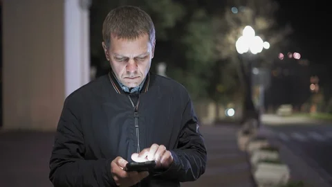 Close-up of a Man Leafing through Contacts on a Smartphone Standing in the Stock Footage 97663917