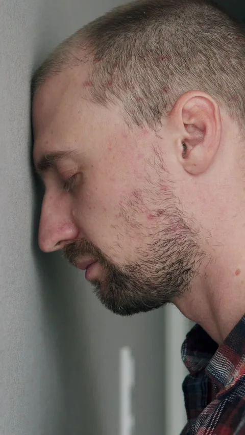 Close-up man leaning head against wall, showing fatigue and depression. Видео 329623610