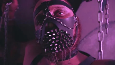 Close up of man in leather face mask chained to bars with handcuff 스톡 동영상 143966093