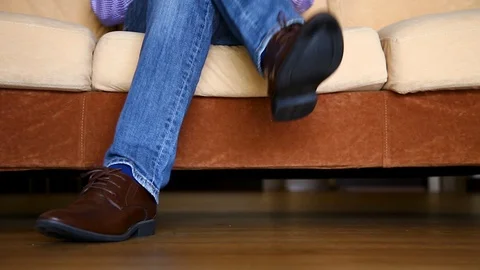 Close up of man leg sitting on sofa Stock Footage 129175098