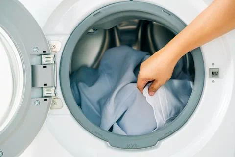 Close up man loading clothes into washing machine. Laundry concept. Stock Photos