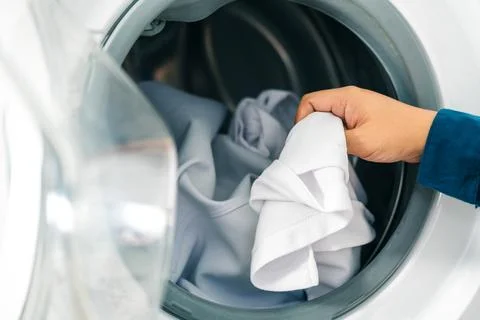 Close up man loading clothes into washing machine. Laundry concept. Stock Photos