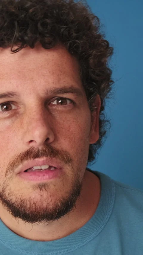 Close-up of man looking at the camera looking for something isolated on blue Stock Footage 252207193