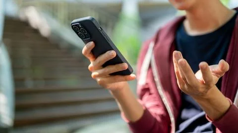 Close up of a man looking at smartphone with doing explaining gesture while.. Fotos Stock