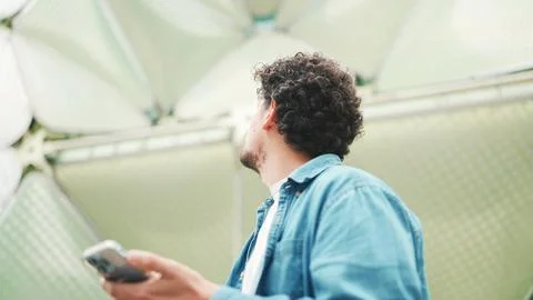 Close-up, man looks at google map on mobile phone and looks around on moder.. 스톡 사진