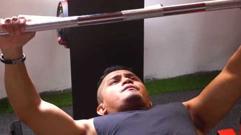 Close-up of a man (lying down) doing a bench press in his personal gym Stock Footage 146499167