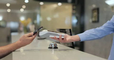 Close up. Man makes nfc payment with mobile phone at pos terminal, paying for Stock Footage 314490812
